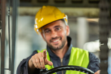 Portrait of forklift truck driver man smiling in old factory warehouse lifting pallet in storage...