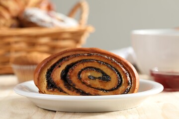 Tasty bun with poppy seeds on table, closeup