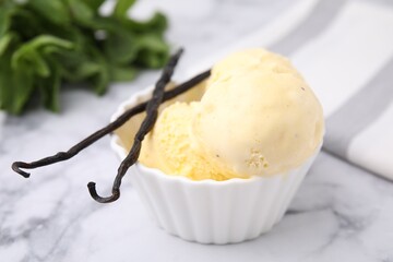 Delicious ice cream and vanilla pods on white marble table, closeup
