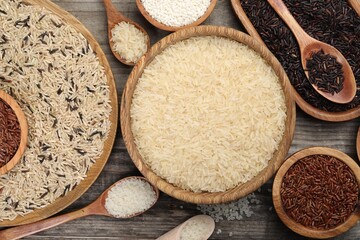 Different sorts of rice on wooden table, flat lay