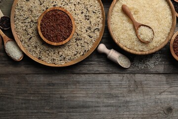 Different sorts of rice on wooden table, flat lay. Space for text