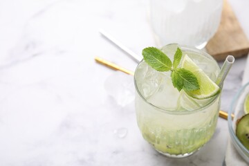 Glass of refreshing drink with lime and mint on white table, closeup. Space for text
