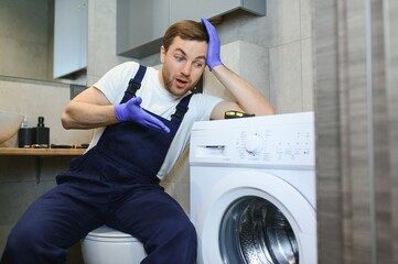 working man plumber repairs a washing machine