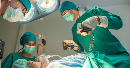 Team of surgery doctor using defibrillator pump chest heart patient to save life while medical surgery in operating room at emergency CPR. Defibrillator in surgeon specialist hand.