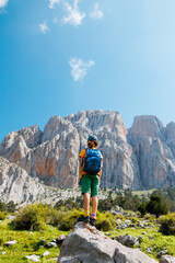 boy with a backpack on a hike against the backdrop of the mountains. child traveler with backpack, hiking, travel, mountains in the background, kids summer vacation.