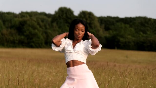 Black woman doing different poses for camera in yellow field during a warm sunny day during sunset.