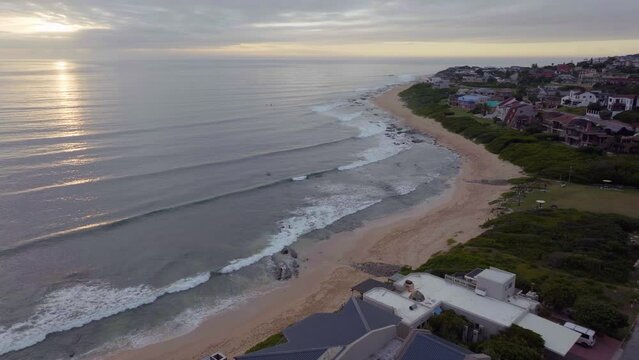 South Africa drone aerial Jeffreys Bay surf town stunning early morning sunrise golden sun on ocean surfer wave groundswell Sunrise sunset drone JBay coastline beach cinematic backward motion