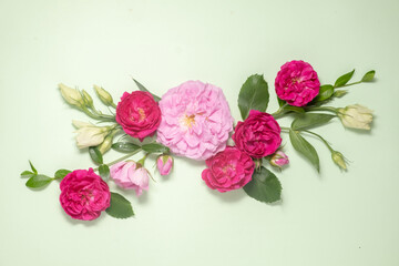 floral layout of pink roses and lisianthus on a soft green background. Top view. Spring or summer floral festive background with copy space.