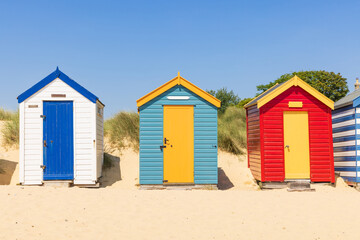 Fototapeta na wymiar Colourful wooden beach huts on the sandy beach in Southwold, Suffolk. UK