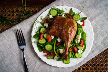 Roast duck salad with pea tendrils, cucumber, chopped tomatoes, and feta cheese.