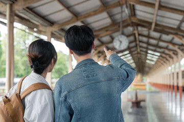 Asian couple travelers, backpack travelers, together at train station platform. tourism activity or railroad trip traveling concept