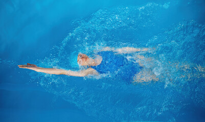 High angle of professional sportswoman swimming in backstroke - obrazy, fototapety, plakaty