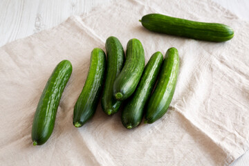 Organic Mini Baby Cucumbers on a white wooden background, side view.