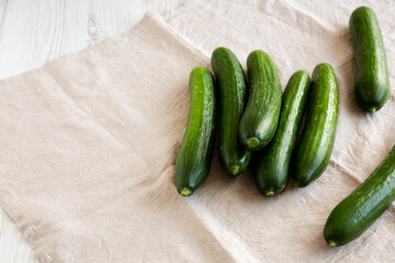 Organic Mini Baby Cucumbers on a white wooden background, side view. Copy space.