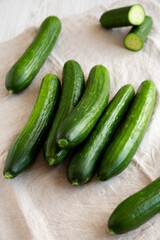 Organic Mini Baby Cucumbers on a white wooden background, side view.