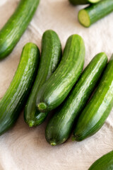 Organic Mini Baby Cucumbers on a white wooden background, side view.