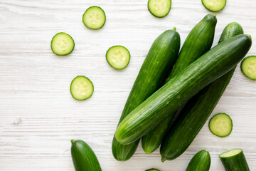 Organic Mini Baby Cucumbers on a white wooden background, top view. Flat lay, overhead, from above.
