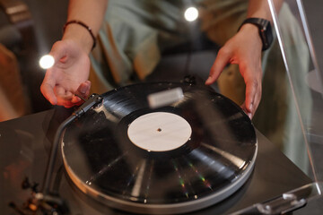 Closeup of black young man using record player at home and enjoying sound quality