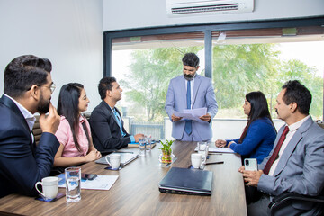 Indian businessman discussing work and plans with employees in boardroom meeting. Corporate presentation business conference.