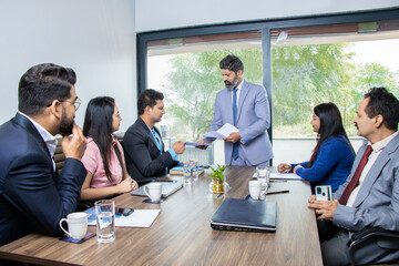 Indian businessman discussing work and plans with employees in boardroom meeting. Corporate presentation business conference.