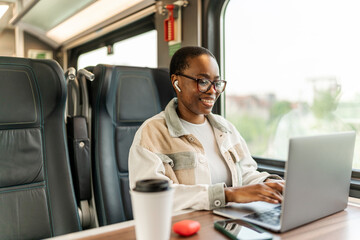 Young business woman traveling to work by train, working while traveling, with her laptop and smartphone during the day.