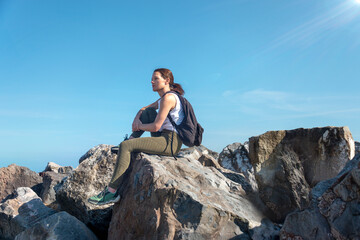 Female walker sitting at a rocky summit enjoying the view above the clouds.