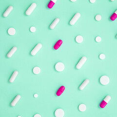 Various colorful medication tablets and capsules on green background. Concept of healthcare and medicine. Top view, pattern