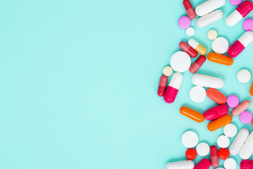 Various white medication tablets and capsules on green background. Concept of healthcare and medicine. Top view, copy space