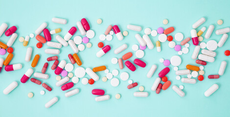 Various colorful medication tablets and capsules on green background. Concept of healthcare and medicine. Top view