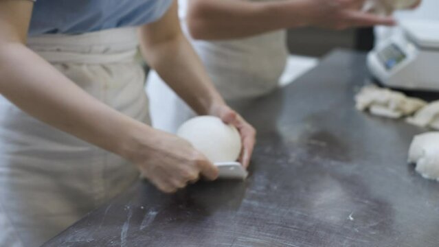 The female hands of the bakery workers separate portions of the dough to be weighed on the scales for making bread. Craft bakery. Production of tasty and healthy bread