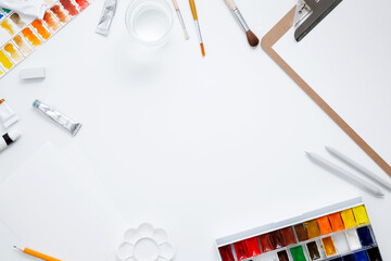 Watercolor, clipboard and other artistic accessories on a white background. Artist's desk...