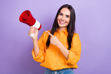Photo of young brunette hair lady wear orange shirt office manager smiling point finger megaphone isolated on violet color background