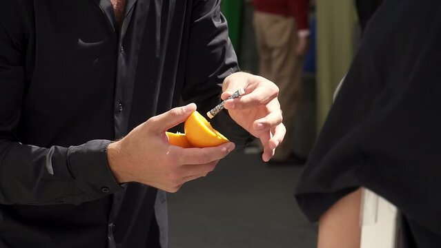 Slow motion shot of a magician revealing money inside of an orange