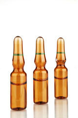 Three ampoules with reflection on a white background. Focus on the central ampoule.