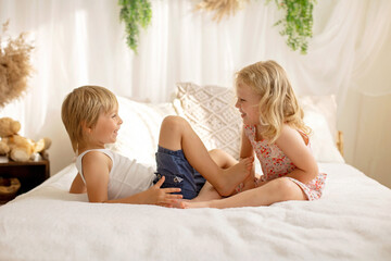 Cute sweet toddler children, tickling feet on the bed, laughing and smiling