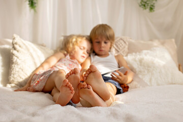 Cute sweet toddler children, tickling feet on the bed, laughing and smiling