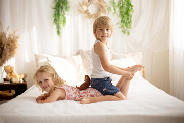 Cute sweet toddler children, tickling feet on the bed, laughing and smiling