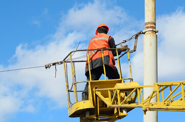 Man ironworker repairing trolleybus rigging standing on a truck mounted lift