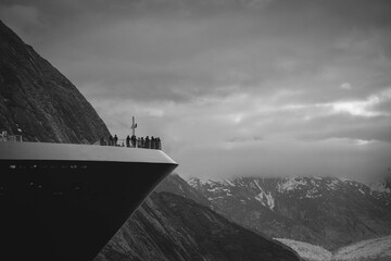 Passengers on bow of cruise ship in Endicott Arm, Alaska looking at distant Dawes Glacier.