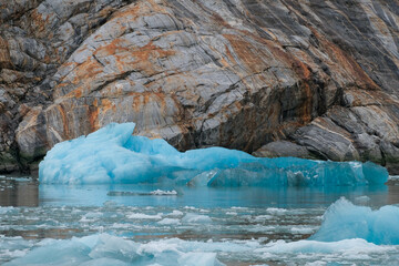 Floating ice and weathered, eroded rock face in Alaska