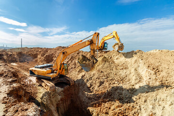Two Excavator are digging soil in the construction site on sky background,with white fluffy cloud
