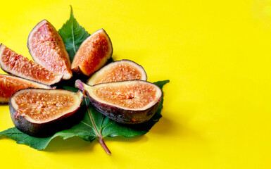 figs with green leaves on yellow background, selective focus. Tropical fruit