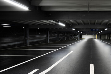 Modern underground garage with lamps illuminating the scene. Parking lines are drawn on the floor. No one inside