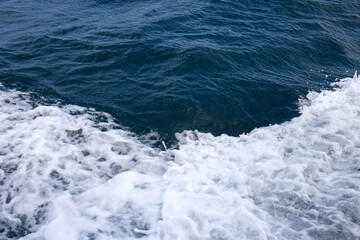 Blue sea waves and white foam from the side of the ship.