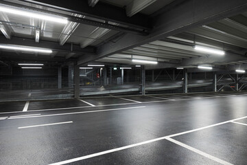 Modern underground garage with lamps illuminating the scene. Parking lines are drawn on the floor....