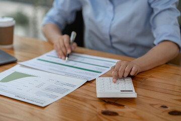 Confident businesswoman working using calculator to calculate profit financial investment document...