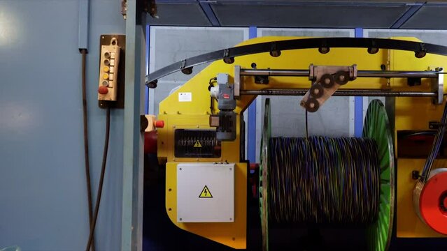 Camera slide in to a large machine that places the electric cable on the rollers, it is stopped to change the roller. The machine is in a special room because it works at very high speed.