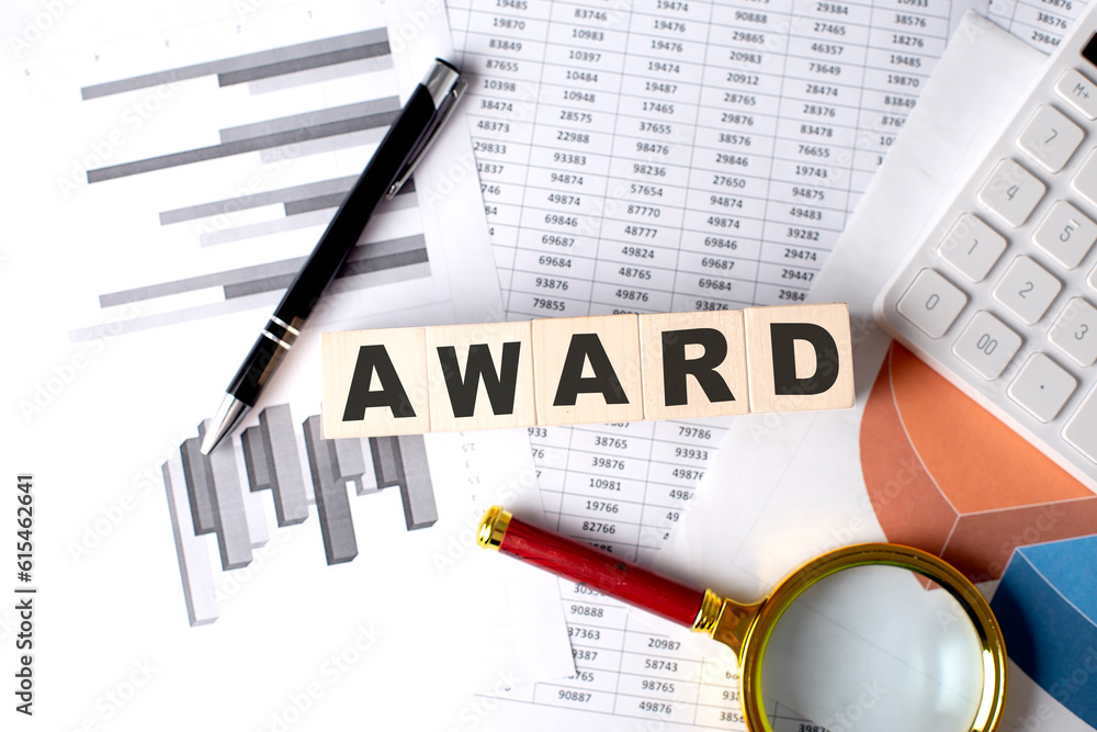 Poster award text on wooden block on graph background with pen and magnifier