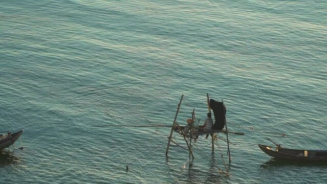 The fisherman is sitting to pull the net to catch Ro Gian's fish on his small hut. Landscape at the mouth of Tra Khuc river, Quang Ngai, Vietnam. View from above.