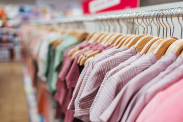 Beautiful baby clothes hanging arranged on rack in a modern store or shop. Shopping interior  concept. No people.